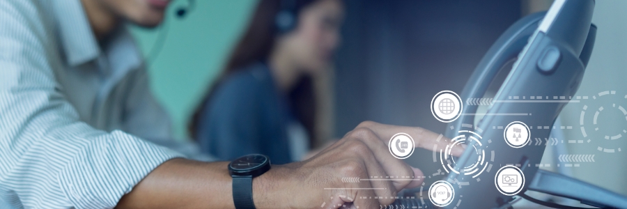 IT support agent typing on laptop with digital communication icons overlay, colleague with headset in background
