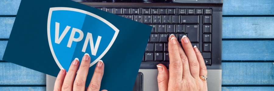 Hands typing on laptop keyboard next to a blue VPN security shield icon for business network protection