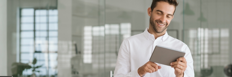 Business professional smiling while reviewing information on a tablet in a modern office environment