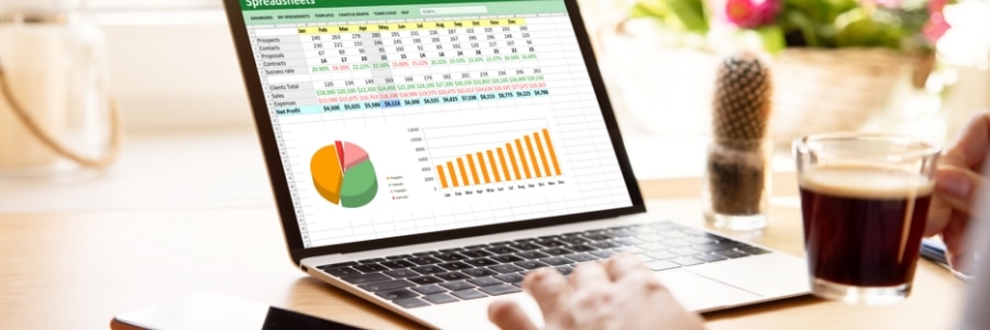 Person working on laptop displaying colorful Excel spreadsheet with pie chart and bar graph data analytics dashboard