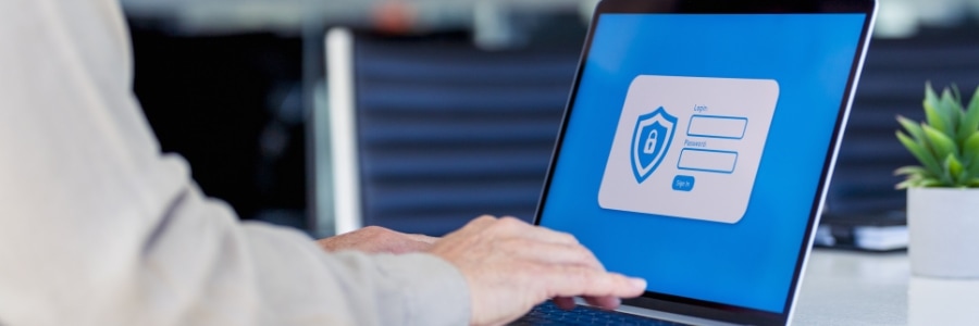 Person typing on laptop displaying a secure login screen with shield icon, managing account privacy settings