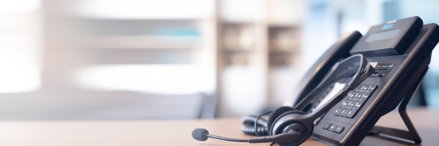 VoIP desk phone and headset on office desk for business communication and IT support