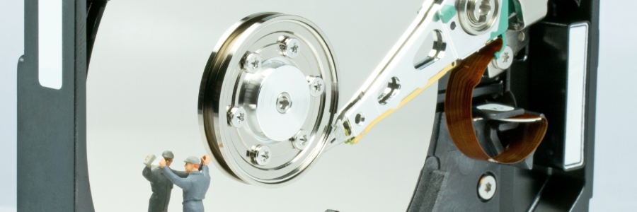 Miniature technicians inspecting open hard disk drive components, illustrating PC hardware maintenance and disk cleanup