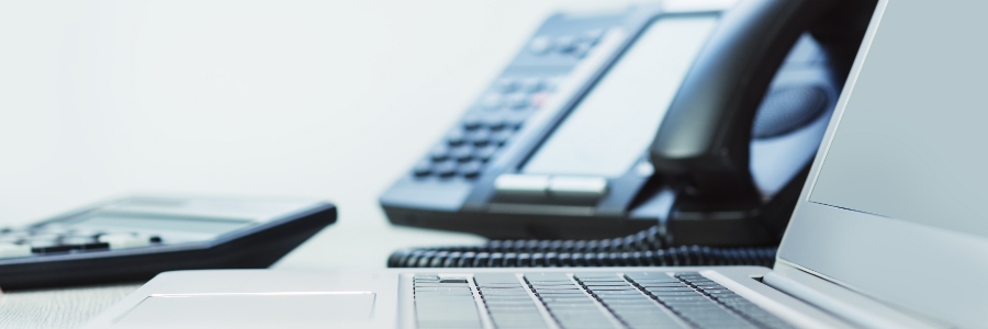 Laptop and VoIP desk phone on office desk representing business communication and IT support solutions