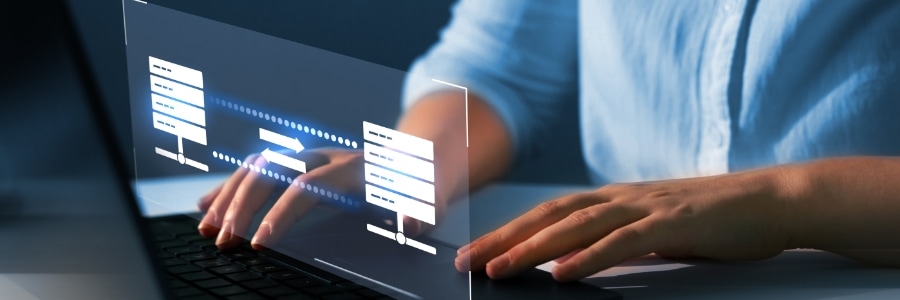 IT professional typing on laptop with holographic server database migration diagram displayed