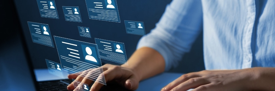 Person typing on laptop with floating digital profile cards displaying user icons and data fields