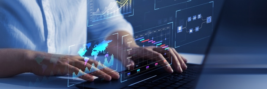 Person typing on laptop with holographic data dashboards, charts, and world map analytics displays floating above keyboard