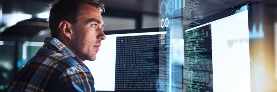 IT professional monitoring multiple screens displaying system logs and cybersecurity data in a dark server environment