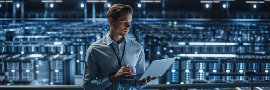 IT professional reviewing laptop in large data center server room