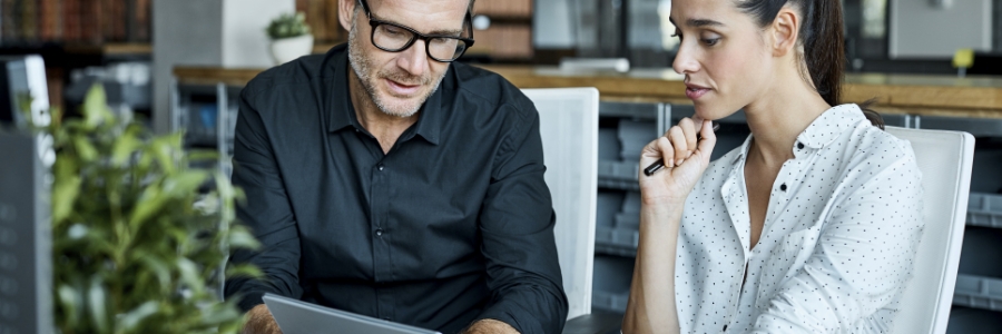 Two business professionals reviewing IT policy documentation together on a tablet in a modern office setting