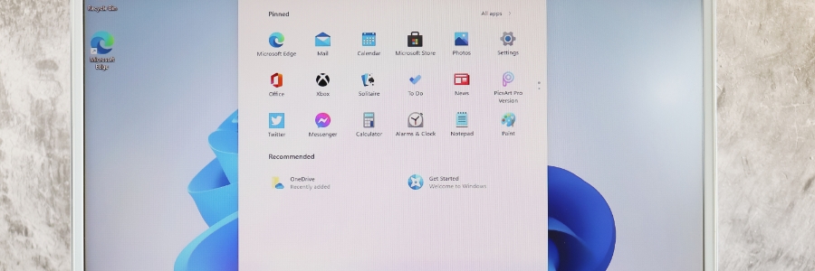 Windows 11 Start menu open on a laptop showing pinned apps including Edge, Office, and Settings icons
