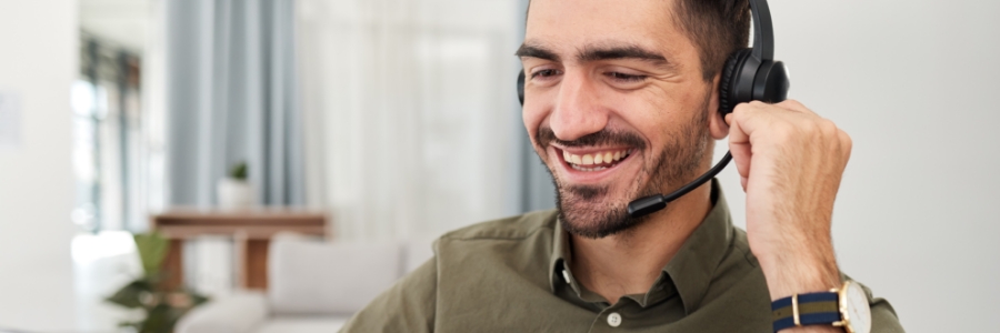 Smiling professional using a headset for a business VoIP call in a modern home office