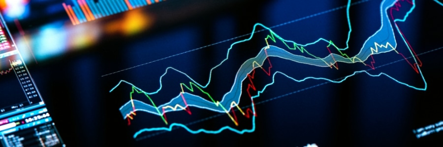 Financial data charts and stock market graphs displayed on a digital trading screen with glowing cyan and green lines