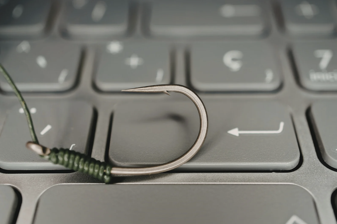 Fishing hook resting on a laptop keyboard, symbolizing phishing cybersecurity threats for small business IT protection