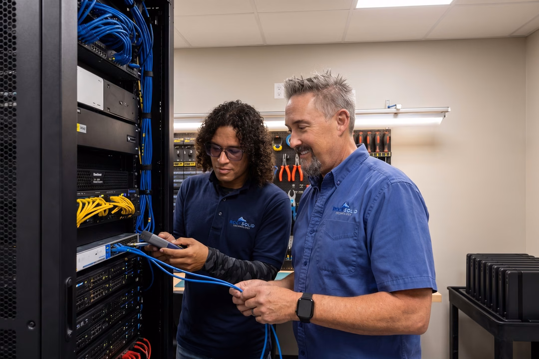 Rock Solid Technology technicians configuring network cables and server rack equipment in a data center