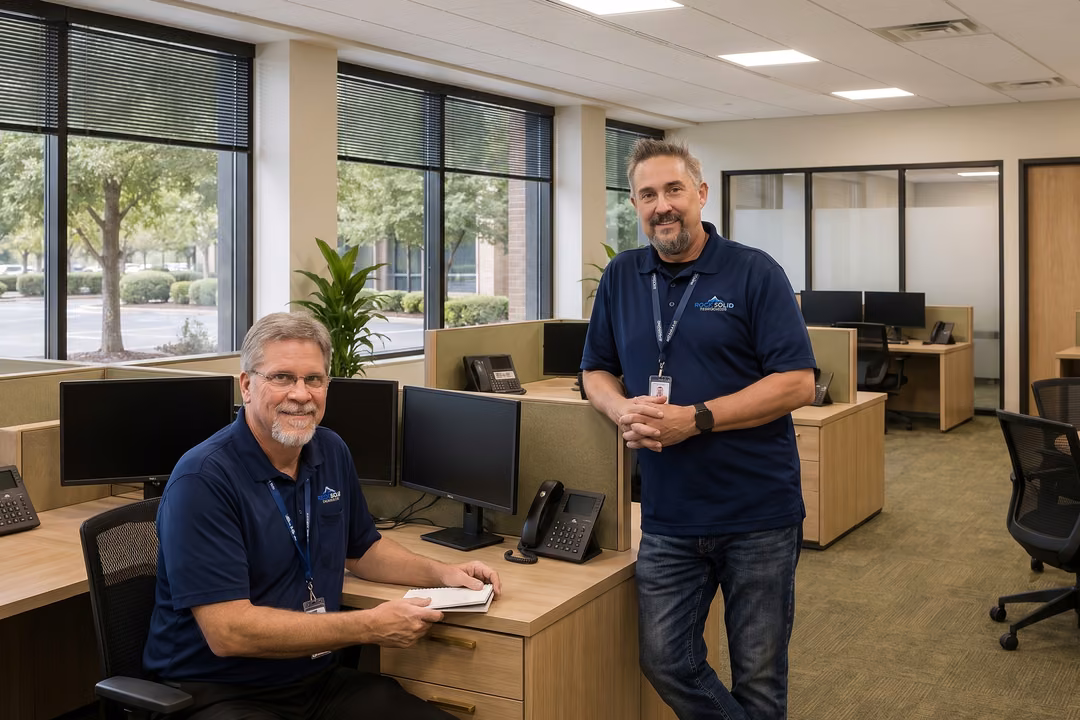 Rock Solid Technology Solutions IT technicians managing endpoints and reviewing support notes at office workstations