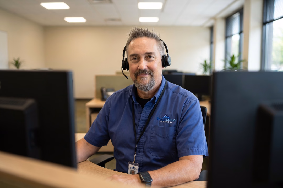 Rock Solid Technology Solutions IT support technician wearing headset working at computer workstation in office