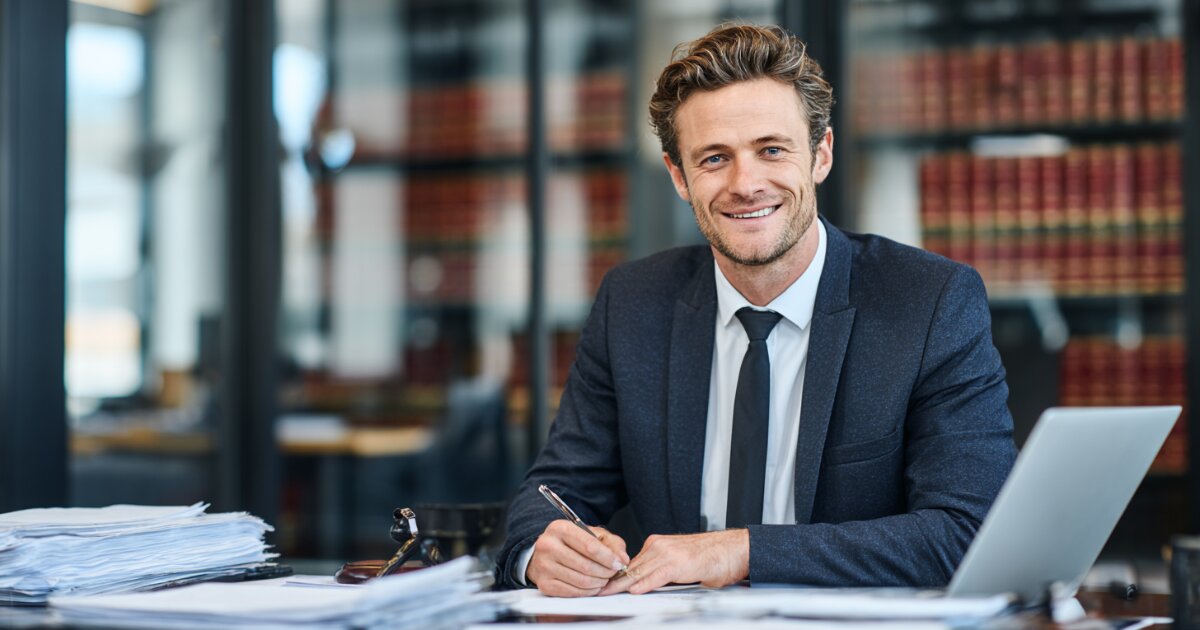 Law firm attorneys consulting with client at conference table in professional office with legal books and scales of justice