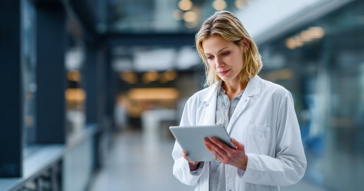 Medical staff reviewing scheduling software on wall-mounted display at clinic reception desk in Thousand Oaks