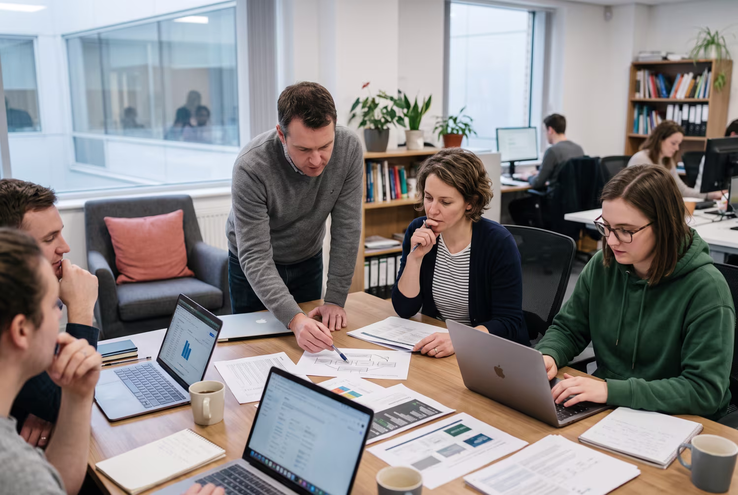 Team discussing IT strategy around cluttered office table