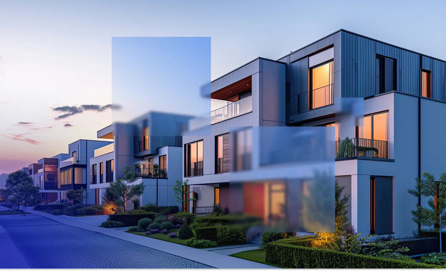 Modern row of white and gray townhouses with large windows and lit interiors at dusk.
