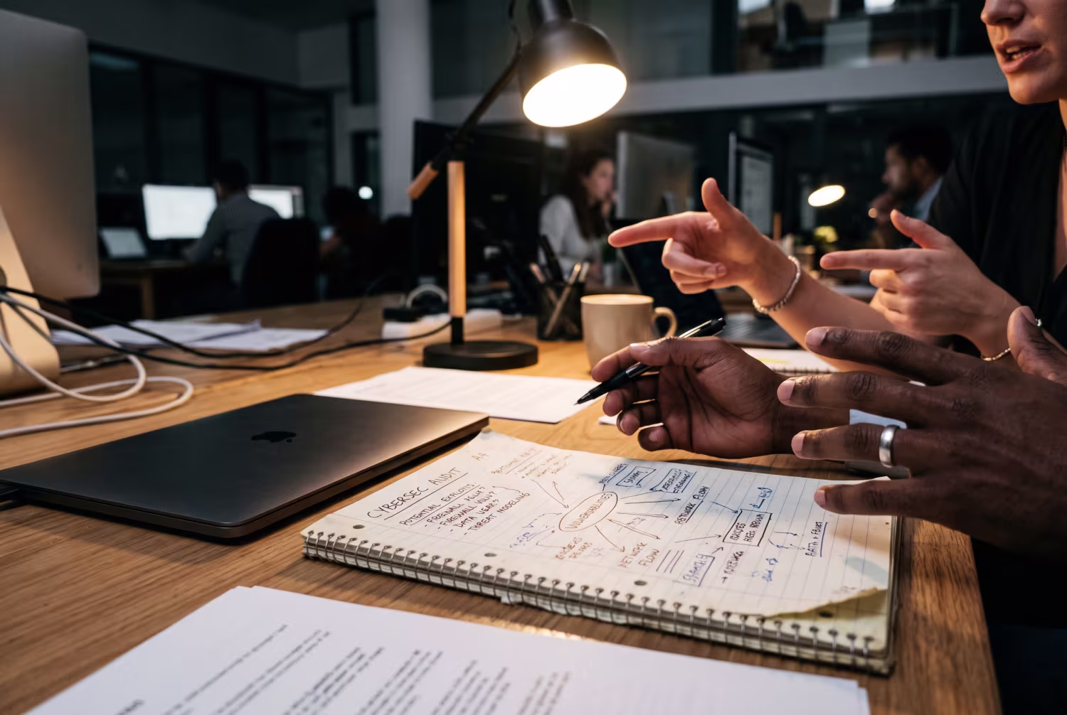 Hands gesturing over notepad with laptop during ransomware recovery brainstorm
