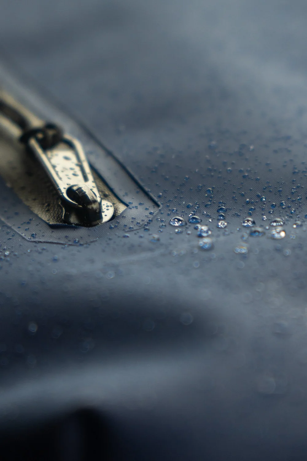 close up of a rain jacket zipper with water bubbles on the jacket