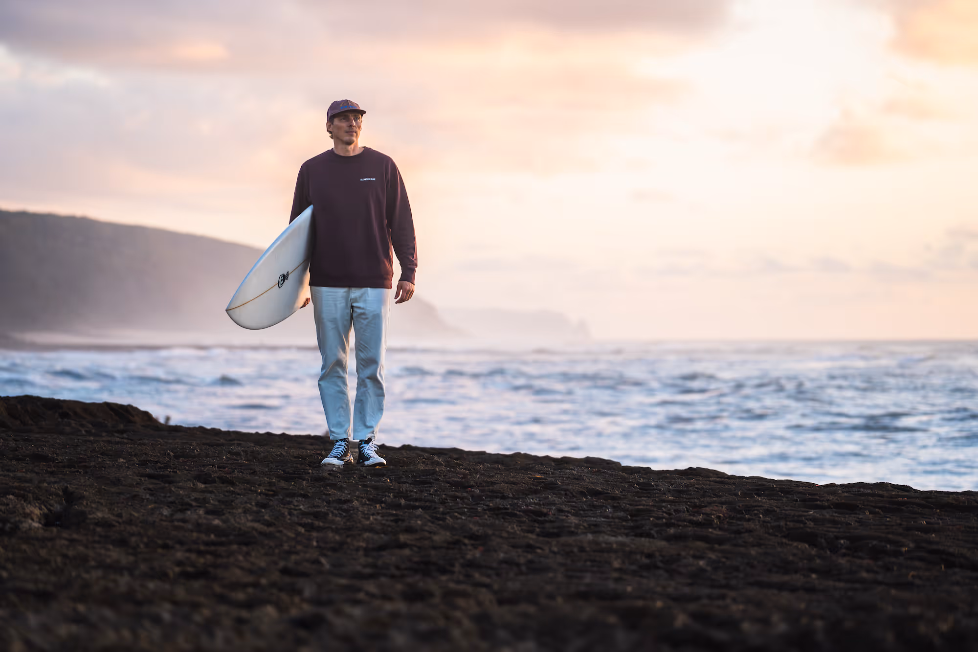 tobias nilting standing in front of a coastline wearing an elevated blue sweater