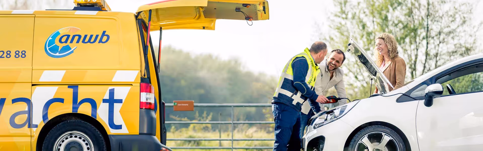 ANWB-pechhulpmedewerker helpt lachend stel bij kapotte auto met open motorkap.