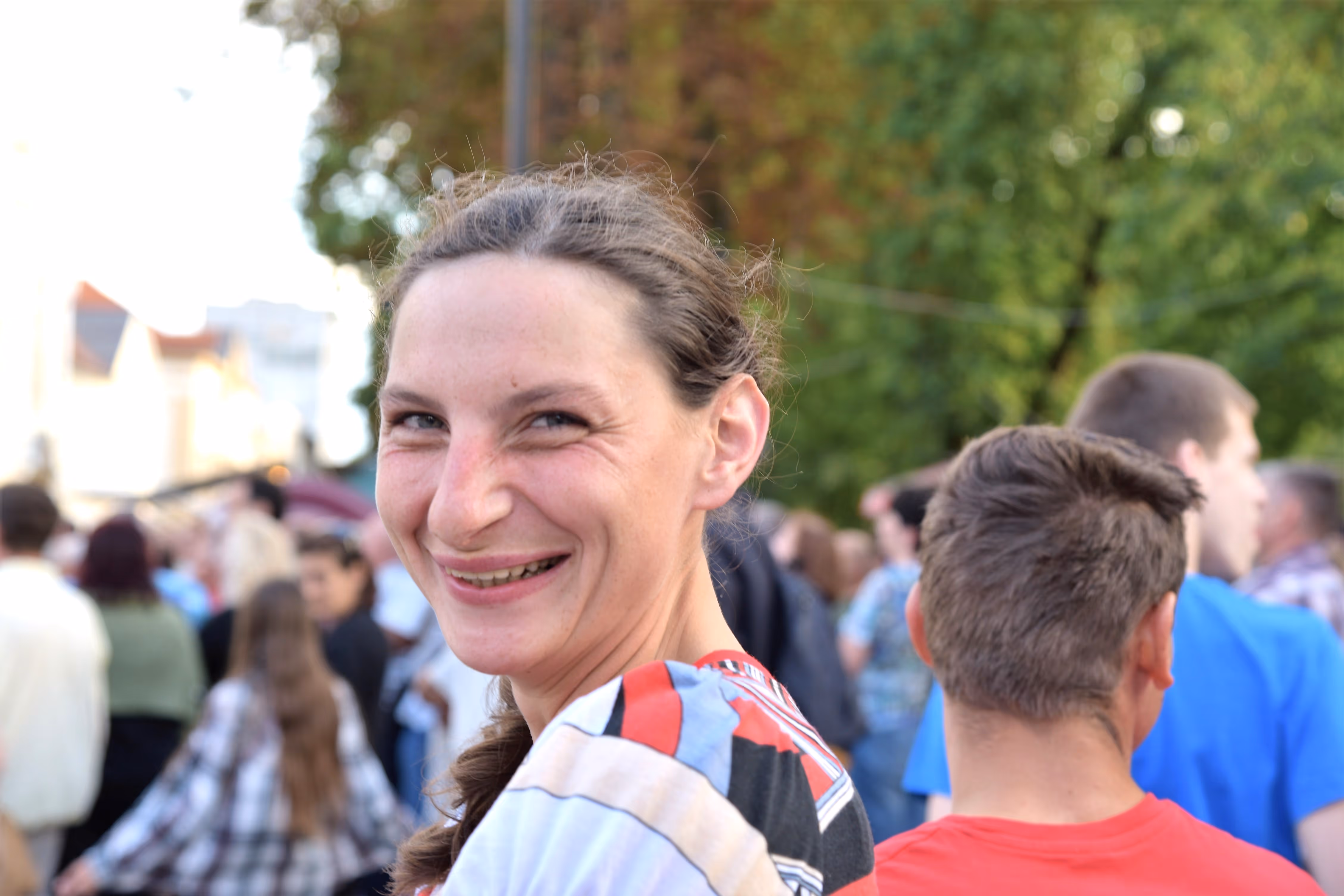 Portret osobe koja se osmjehuje u gomili na otvorenom događanju
