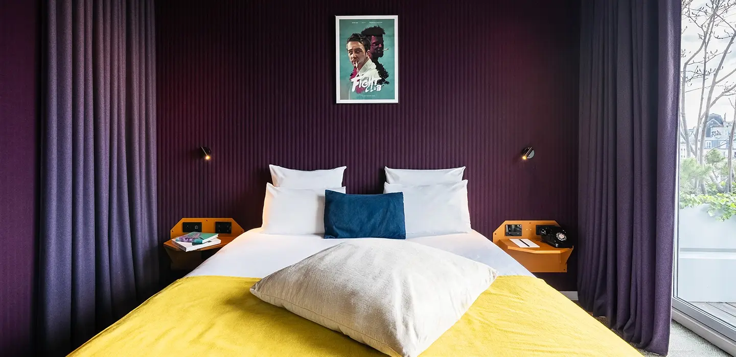 Recadrage vertical resserré sur le lit à couverture jaune et coussins bleu marine, sous l'affiche du film Fight Club