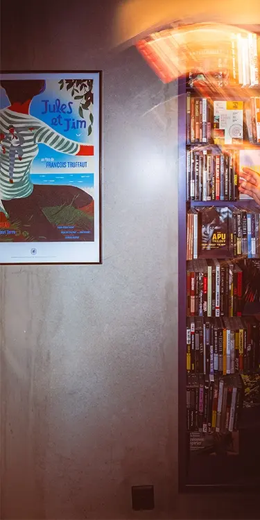 Recadrage vertical montrant l'affiche encadrée de Jules et Jim au mur, face à une étagère de DVD éclairée en filé lumineux
