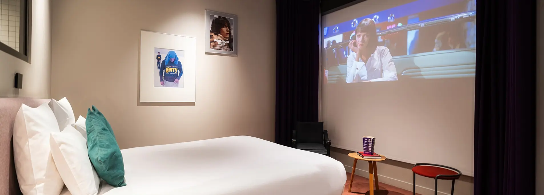 Chambre lit blanc à coussin bleu canard, projection cinéma murale et affiches de films encadrées