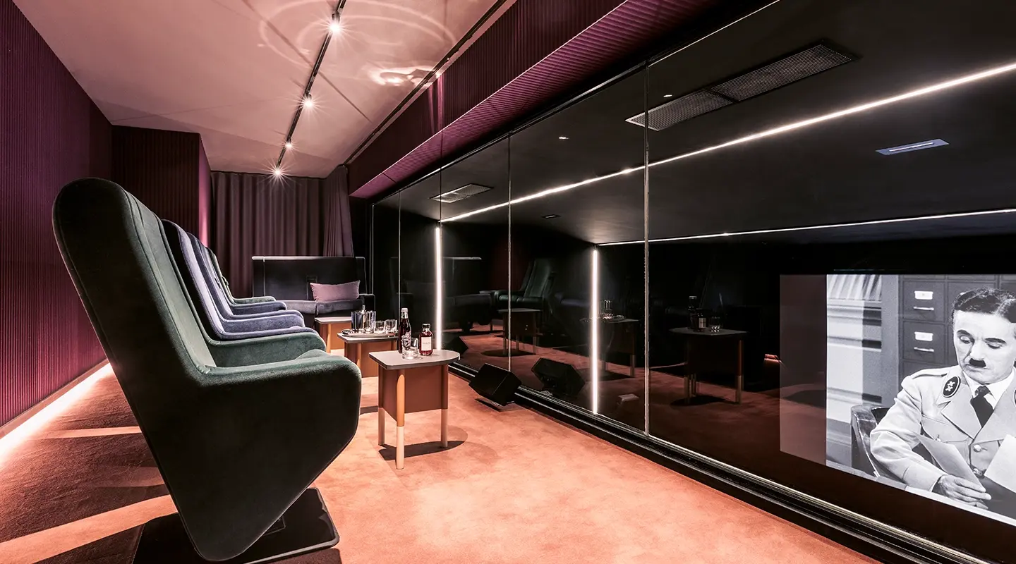 Close-up vertical crop of reclining chairs in a private home theater, with side tables featuring a bottle and glasses