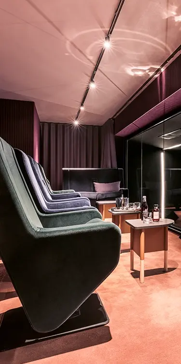 Close-up vertical crop of reclining chairs in a private home theater, with side tables featuring a bottle and glasses