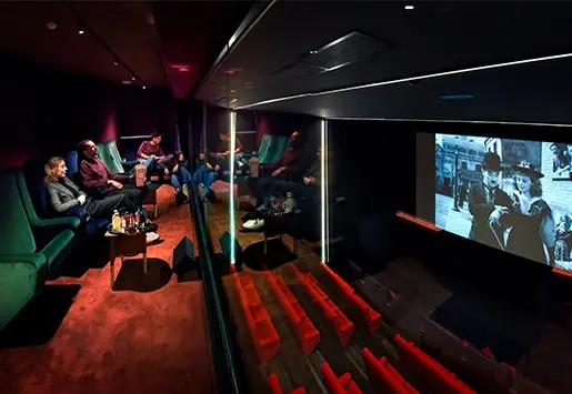 Private box overlooking a movie theater where a group of friends is watching a classic black-and-white film.