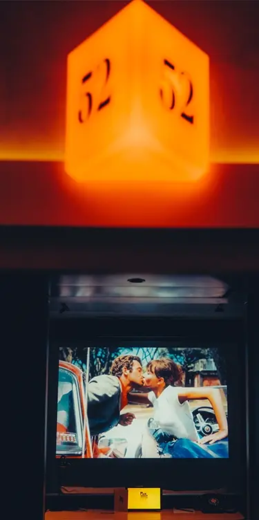 Vue en gros plan format portrait de la pancarte lumineuse orange chambre 52, écran de projection en contrebas
