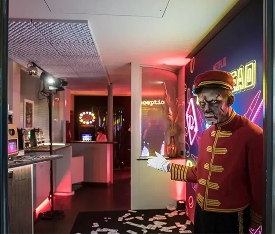 Zombie bellhop greeting visitors in a neon-lit hotel lobby.