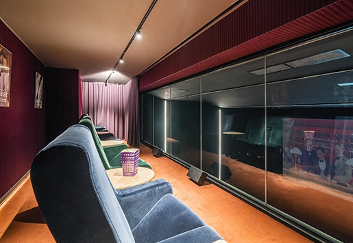 Private cinema room with a row of blue and green velvet armchairs facing a bay window overlooking the screen.