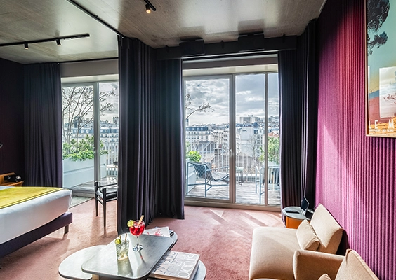 Suite d'hôtel moderne avec lit double, coin salon et terrasse privée.