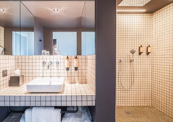 Salle d'eau moderne en petit carrelage beige avec lavabo à poser et douche à l'italienne.
