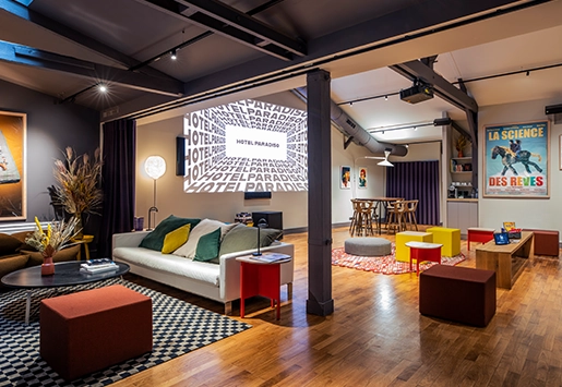 Spacious open-plan loft with a contemporary style, featuring a cozy lounge area, a space with a projector, and plenty of colorful seating.