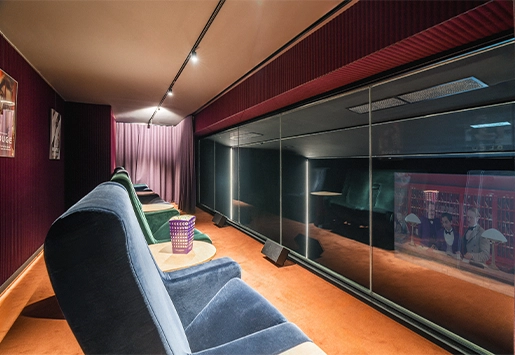 Private screening room featuring velvet armchairs and a large picture window overlooking the screen.