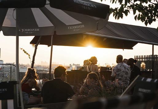 Cozy rooftop illuminated by string lights at dusk, offering a panoramic view of the city skyline and the Eiffel Tower.