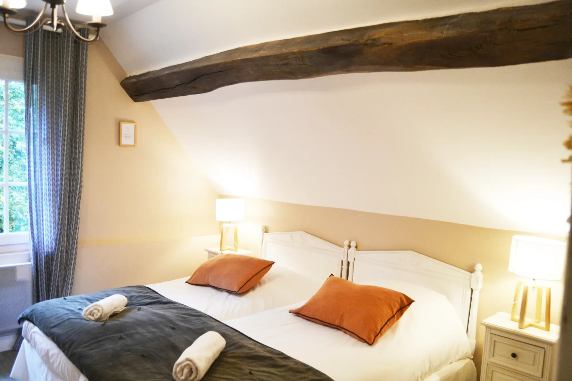 A cosy room with a double bed, exposed beams and natural light