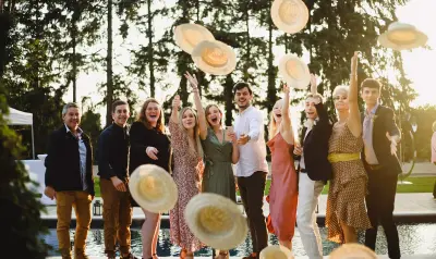 Groupe de personnes joyeuses lançant des chapeaux de paille en l'air lors d'une fête en plein air.
