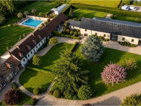 Vue aérienne d'un domaine avec grange rénovée, parc arboré et vastes champs verdoyants à perte de vue