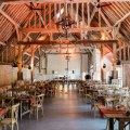 Salle de restaurant spacieuse avec charpente en bois et tables élégamment dressées.