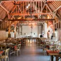 Salle de restaurant spacieuse avec charpente en bois et tables élégamment dressées.
