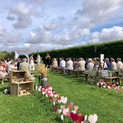 Cérémonie de mariage en plein air avec invités assis sur des bancs en bois et décorations florales.